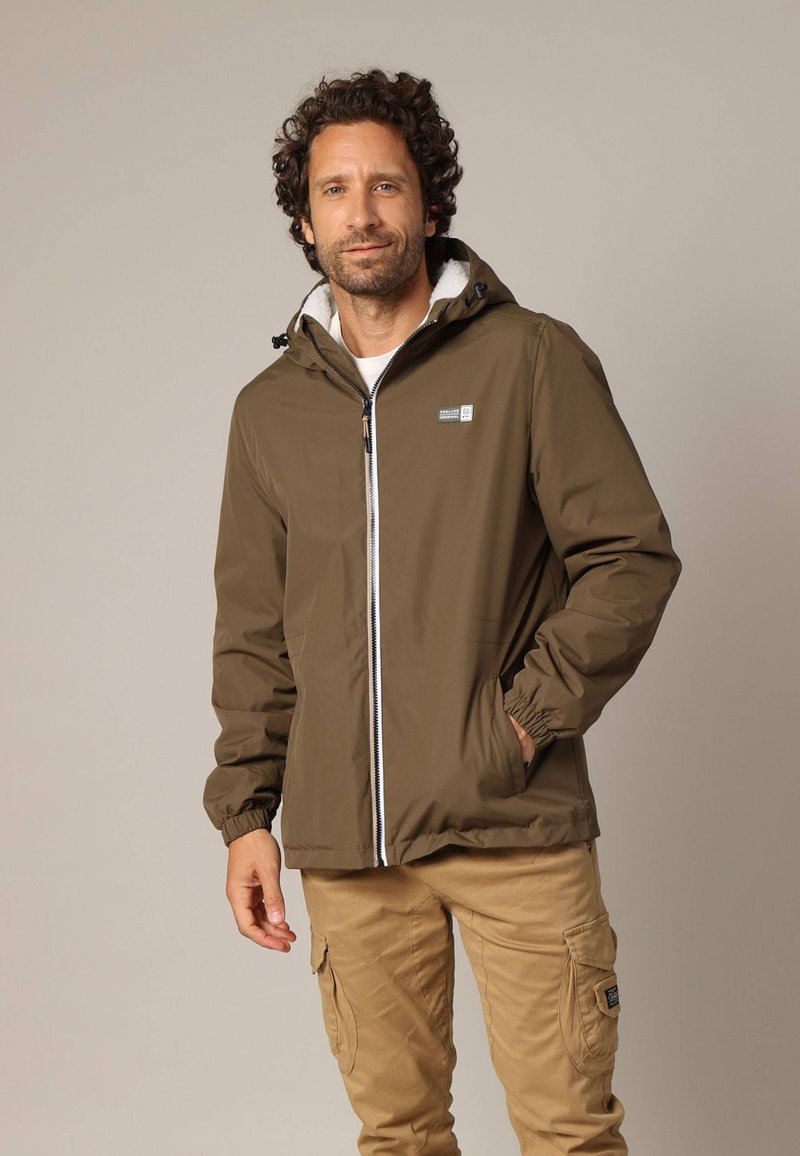 Olijfgroene hoodie-jack met een witte rits en elastische manchetten. Heeft een zachte binnenvoering en een klein logo-opdruk op de borst.