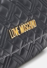 Svart kviltad syntetläderväska med en guld "LOVE MOSCHINO"-logotyp. Utmärkande diamantmönster och en mjuk textur.