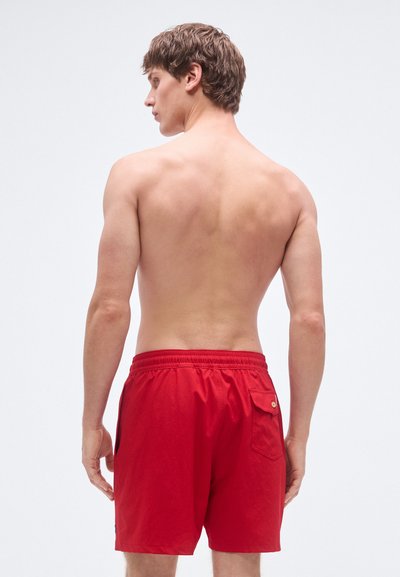 Calções de banho vermelhos com cintura elástica, bolso traseiro e corte confortável. Feitos de material leve com textura suave.