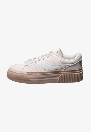 Zapatilla Nike de corte bajo en rosa claro y beige con el símbolo Swoosh blanco, cierre de cordones y suela gruesa y texturizada.