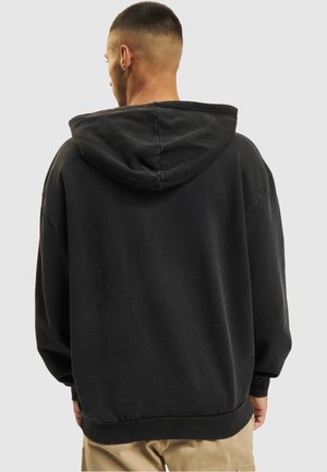 Felpa con cappuccio nera oversize in tessuto morbido, con cappuccio regolabile, spalle scese e polsini e orlo a coste. Design semplice.