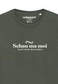 Donkergroene t-shirt met een ronde halslijn. Voorzien van witte tekst, "Schau ma moi DAN SENG MAS SCHI!" die prominent op de voorkant is afgedrukt.