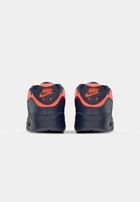 Blå och orange Nike Air sneakers med en texturerad baksida, utrustade med en orange logotyp och en vadderad sula för komfort.
