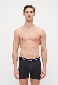 Pánske tmavosivé boxerky so čiernym elastickým pásom a bielym logom "Champion". Hladká textúra, priliehavý strih, dĺžka nad stredným stehnom.