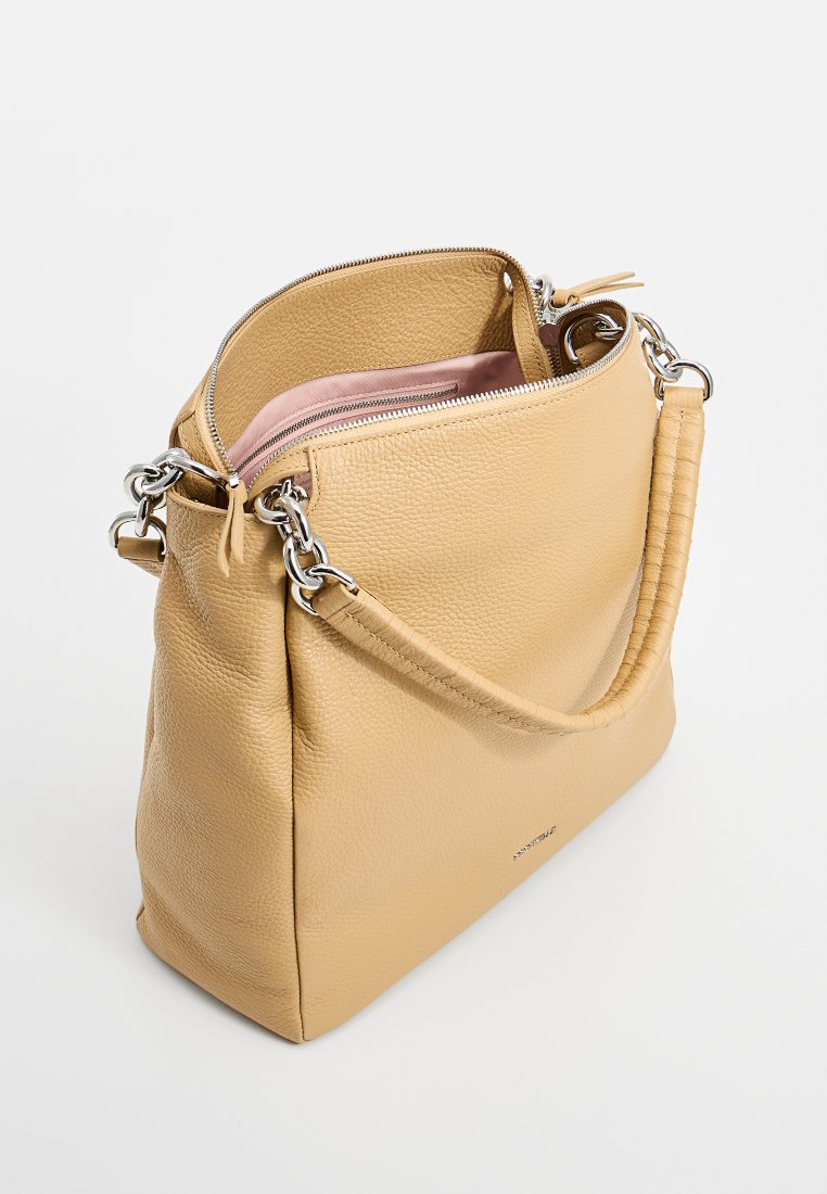 Dzeltena ādas rokassoma ar teksturētu virsmu, ar rāvējslēdzēju un sudraba ķēdes akcentiem. Iekšpusē ir mīksts rozā odere.