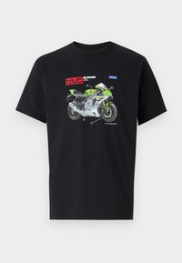 Zwarte katoenen t-shirt met een grafisch ontwerp van een groene en witte motorfiets met gelabelde onderdelen en "HUF" branding erboven.
