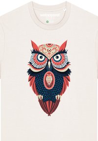 Cremfarbener T-Shirt mit einem detaillierten Eulendesign in Blau, Rot und Creme, versehen mit kreisförmigen Mustern und Akzenten. Standard Rundhalsausschnitt.