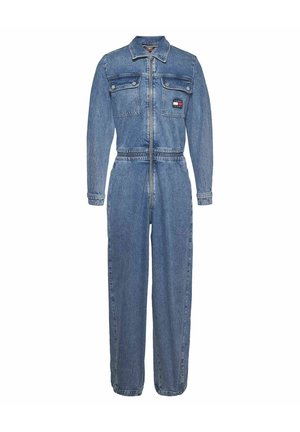 Combinaison en denim à manches longues, fermeture éclair à l'avant et taille ceinturée. Présente deux poches poitrine et un patch logo sur la poche gauche.