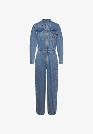 Combinaison en denim à manches longues, fermeture éclair à l'avant et taille ceinturée. Présente deux poches poitrine et un patch logo sur la poche gauche.