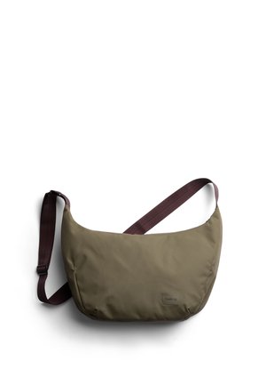 Sac bandoulière vert olive avec une finition douce et texturée, doté d'une sangle bordeaux et d'un petit logo sur le devant. Forme arrondie, design minimaliste.