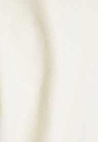 Tessuto spesso color bianco sporco con una superficie morbida e testurizzata, che mostra variazioni sottili e un aspetto leggermente tessuto.