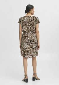 Klänning i leopardmönster tillverkad av mjukt tyg, med rund halsringning, korta ärmar och en samlad detalj på baksidan. Kombinerad med blockklacksandaler.