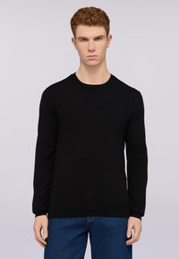 Černý svetr s dlouhými rukávy a kulatým výstřihem, vyrobený z měkkého materiálu. Jednoduchý design bez viditelných vzorů nebo akcentů.