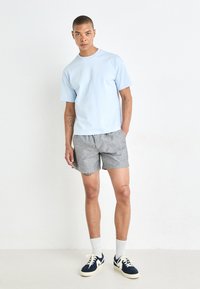 Light blue short-sleeve shirt, gray striped shorts, white socks, and navy sneakers. Simple design with a relaxed fit and casual style.