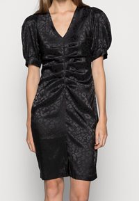 Black satin dress with a V-neckline, puff sleeves, and ruched detailing. Features subtle leopard print and a slit at the hem.