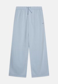 Lyseblå vidbenede joggebukser med elastisk liv og snøring. Har subtil merking på siden. Myk stofftekstur.
