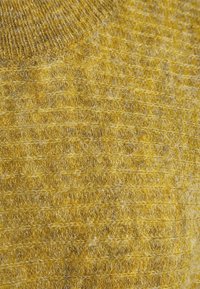 Close-up of textured yellow knitted fabric with visible fibers and horizontal ribbed pattern.