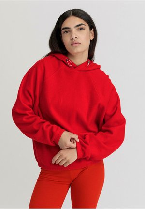 Rode fleecetrui met een trekkoord in de capuchon, raglanmouwen en een relaxed fit, gecombineerd met bijpassende rode broek. Zachte textuur en effen kleur.