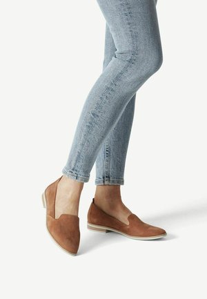 Ballerines en suede marron avec un petit talon, présentant un design en V et un bout arrondi. Associées à un jean skinny bleu clair.