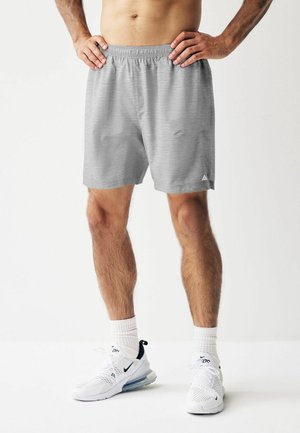 Grå sports shorts med elastisk talje, en subtil meleret struktur og en lille logo detalje i kanten. Bæres med hvide sneakers.