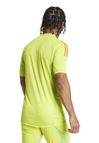 Maglietta sportiva a maniche corte di un vivace verde lime con accenti arancioni e una finitura testurizzata, progettata per comfort e prestazioni.