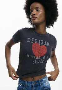 Mustast pehmetest materjalidest lühikeste varrukatega T-särk, millel on punase südame graafik ja valge tekst. Kandmisega seotud sinised teksad, mis esitavad keskosa.