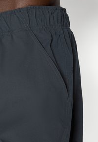 Donkergrijze sportshorts van lichtgewicht stof, met een elastische tailleband en zijzakken met subtiele stikdetails.