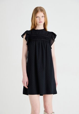 Vestido corto negro con tela texturizada, mangas con volantes y detalles fruncidos en el cuerpo. Silueta simple y fluida.