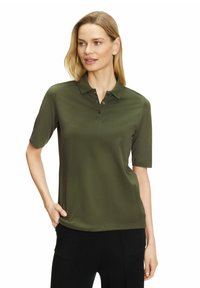 Korte mouwen polo in donkergroene stof, met een kraag en drie knopen en een ontspannen pasvorm. Gladde textuur, minimale details.