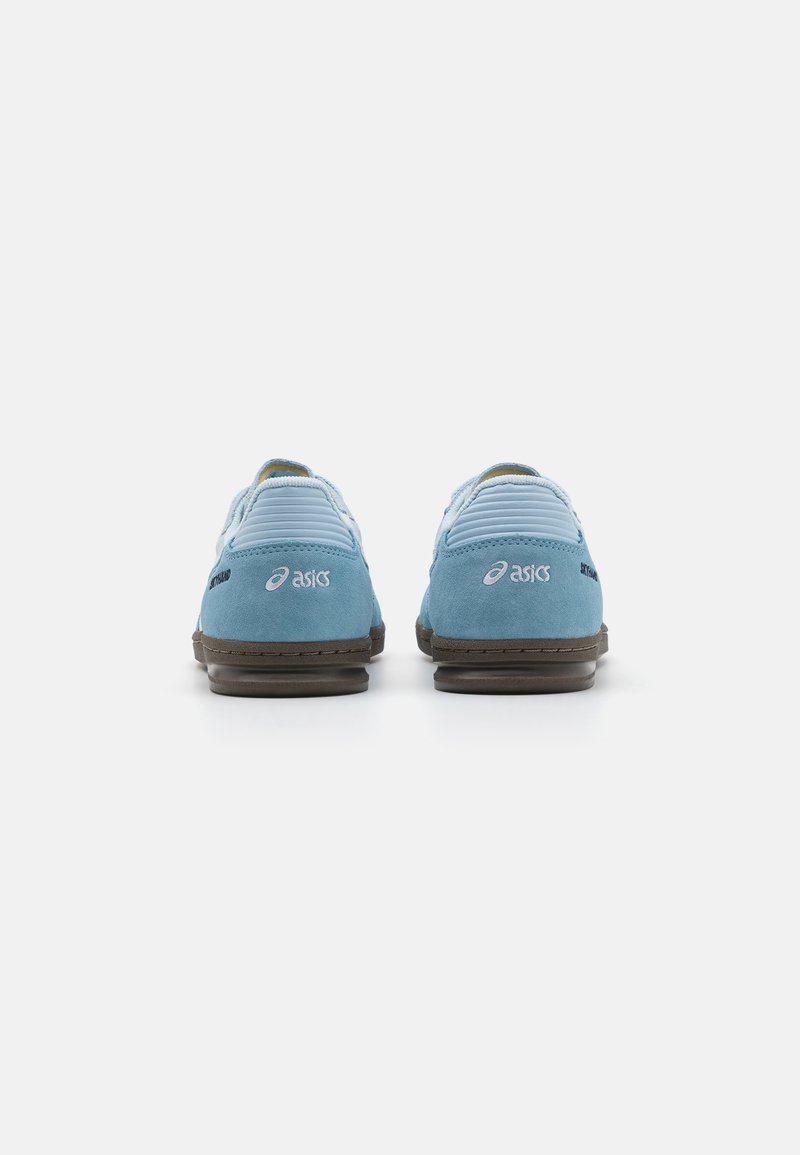 Zapatillas deportivas de ante azul con un acabado texturizado, que cuentan con una suela de goma marrón y un detalle de marca blanca en el talón y el costado.