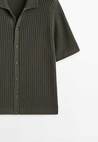 Cardigan tricoté vert foncé à manches courtes avec un motif côtelé et une fermeture boutonnée sur fond blanc.