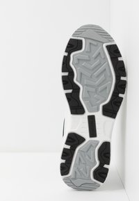 Skechers idrettssko såle, med en hvit og grå teksturert gummibase med svarte aksenter og sikksakk-mønster for grep.