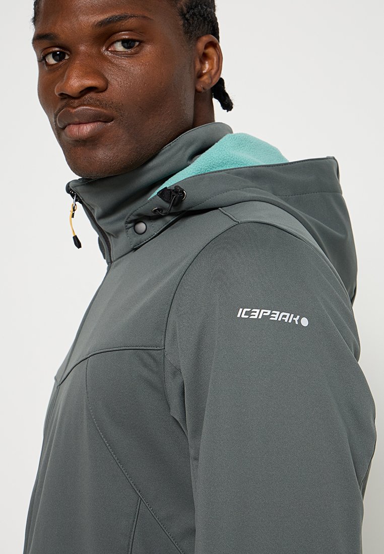 Veste imperméable grise avec capuche, dotée d'une doublure en polaire bleu clair, d'accents noirs et d'un logo sur l'épaule gauche. Texture lisse.