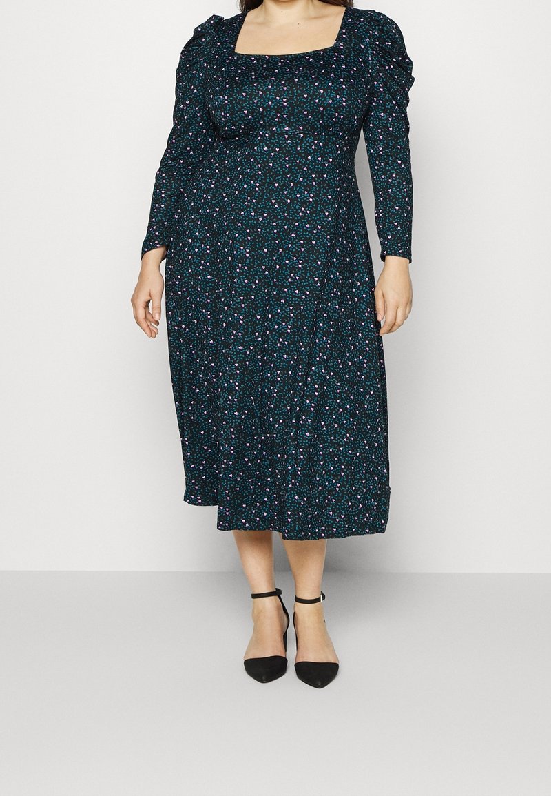 Robe à manches longues couleur bleu sarcelle foncé avec un décolleté carré, ornée d'un motif floral en rose et violet, longueur mi-mollet, tissu léger.