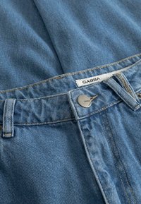 Jeans in denim azzurro chiaro con un classico design a cinque tasche, cuciture gialle, etichetta marchiata e chiusura con bottone in metallo.