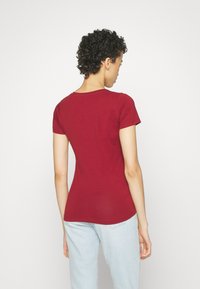 Raudonas trumpas rankovė t-shirt su apvaliu kaklu ir prigludusia dizainu, pasižymintis lygiu paviršiumi ir vienoda nugara be raštų.