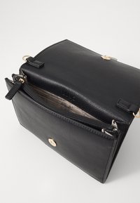 Borsa a mano in pelle nera con un design strutturato, dotata di una chiusura a scatto in tonalità oro, tasca interna con zip e una superficie testurizzata.