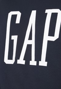 Marineblauwe sweatshirt met grote witte "GAP" letters. Heeft een zachte, gestructureerde stof en een ronde halslijn, wat zorgt voor een casual pasvorm.