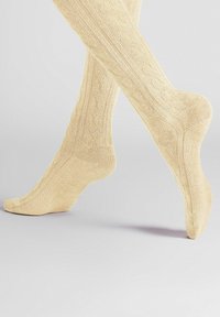 Beige kniehohe Socken mit einem strukturierten Rippenmuster, nahtloser Spitze und glatter Oberfläche. Hergestellt aus einem weichen, dehnbaren Stoff.
