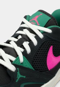 Κοντινή λήψη μαύρου αθλητικού παπουτσιού με λευκές κορδόνες, πράσινες και ροζ λεπτομέρειες, ροζ λογότυπο Nike και πράσινο λογότυπο Jumpman στη γλώσσα και στο πλάι.
