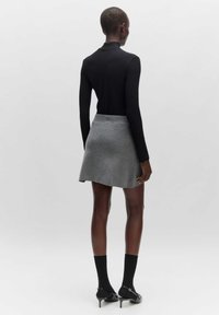 Zwarte geribbelde lange mouwen top gecombineerd met een grijze flared mini rok. De rok heeft een zachte textuur en sluit mooi aan. Zwarte panty’s en hakken.