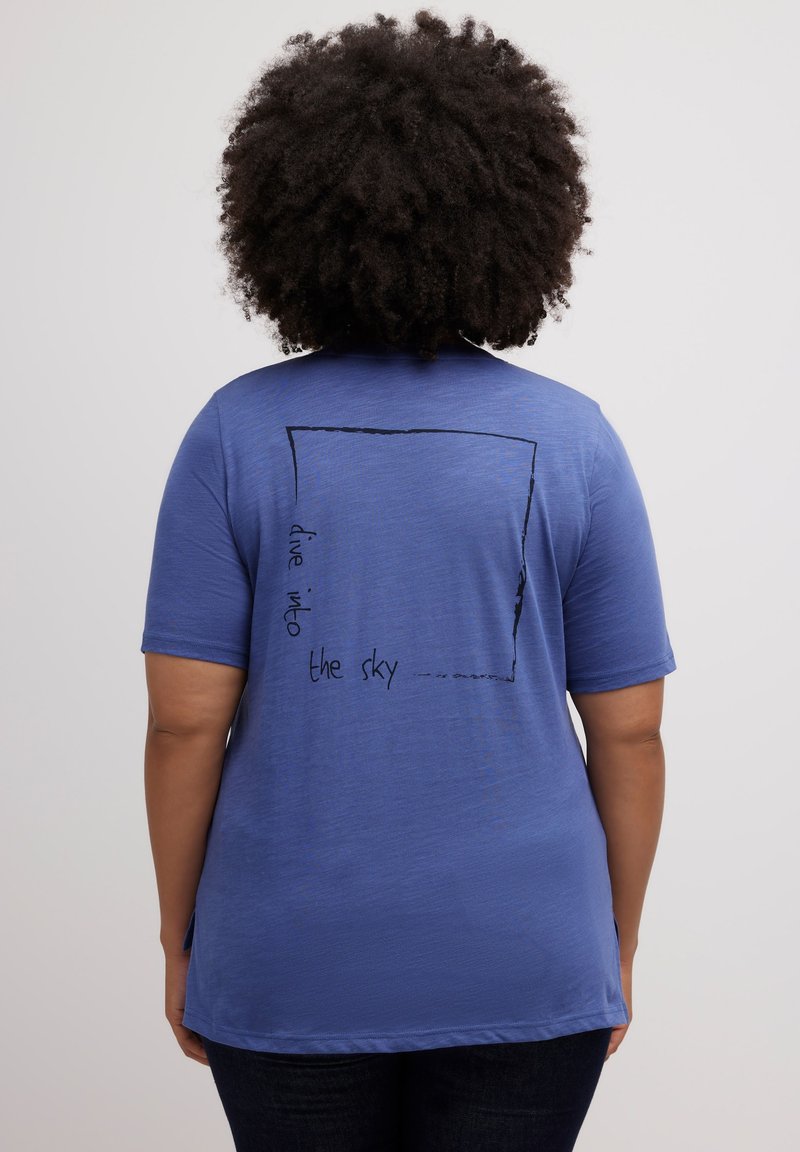 Blauwe t-shirt met korte mouwen met een vierkante afbeelding en de tekst "duik in de lucht" in het zwart gedrukt op de achterkant, gemaakt van een zachte, gestructureerde stof.