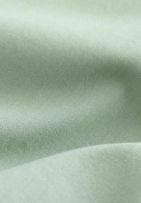 Puha zöld textil anyag, sima, matt felülettel, finom fényváltozásokkal és egységes szövésmintával.