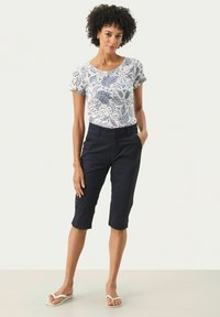 T-shirt blanc avec un motif floral bleu marine, manches courtes, assorti à un short bleu marine à mi-cuisses et des tongs blanches. Tissu lisse et coupe décontractée.