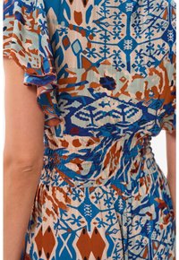 Monivärinen mekko, jossa on sininen, ruskea ja kermaabstract kuosi. Valmistettu tekstuurikankaasta, jossa on röyhelöhiha ja smockattu vyötärö.