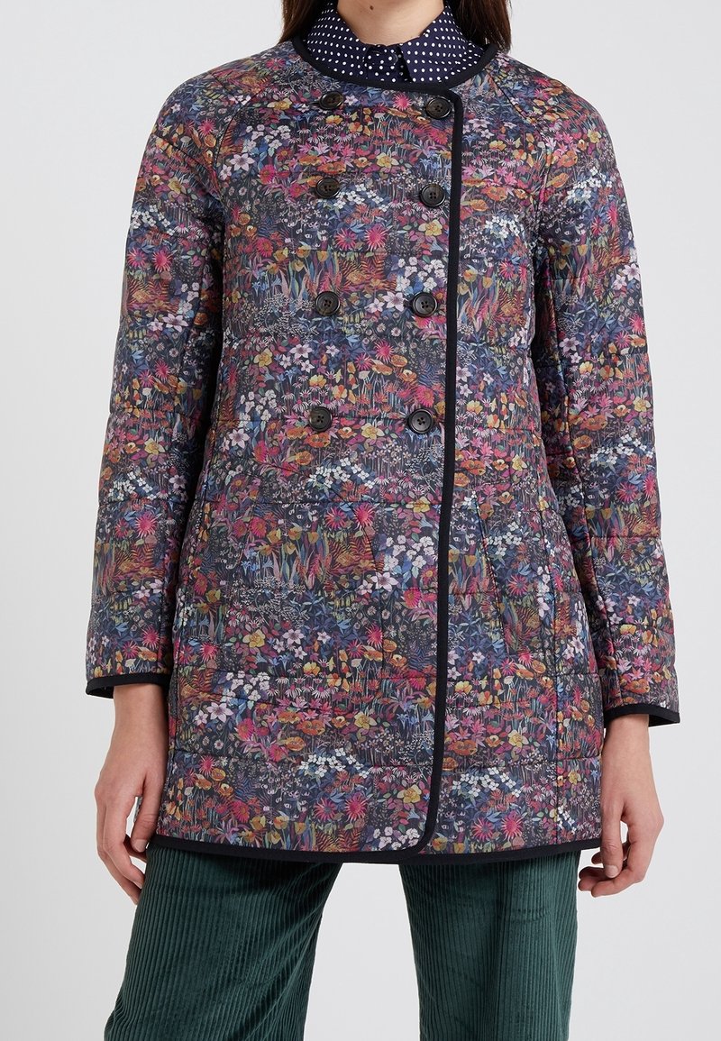 Vaatteet itse asiassa tummalla kukkakuviolla, jossa on kirkkaat värit. Takissa on pyöreä pääntie, kaksinkertainen edestä napitus ja mustat yksityiskohdat.