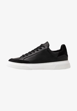 Sneaker in pelle nera con accenti in suede e suola in gomma bianca. Presenta punta arrotondata e chiusura con lacci. Dettaglio di cuciture sottili su tutta la superficie.