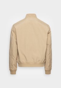 Beige bomber jacket s límcem, žebrovanými manžetami a lemem, vyrobená z hladkého materiálu s minimalistickým designem.
