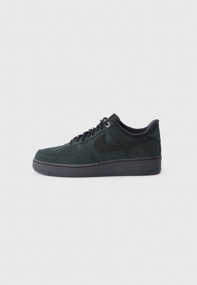 Nike Air Force 1 kedas tumši zaļā zamšā ar melniem akcentiem, teksturētu augšdaļu, apaļu purngali, un gumijas zoli. Iekļauj saites aizdari.