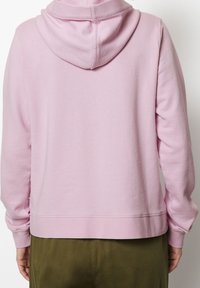 Sudadera con capucha rosa de corte relajado, puños y dobladillo acanalados. Textura suave, tejido ligero y un acabado limpio en la parte posterior.